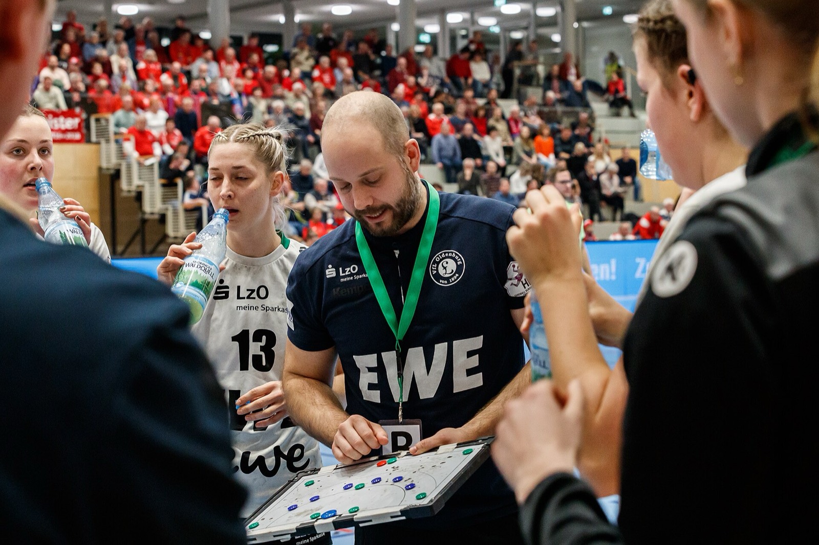 Handballtrainer erklärt seinem Team in der Auszeit eine Szene auf der Taktiktafel